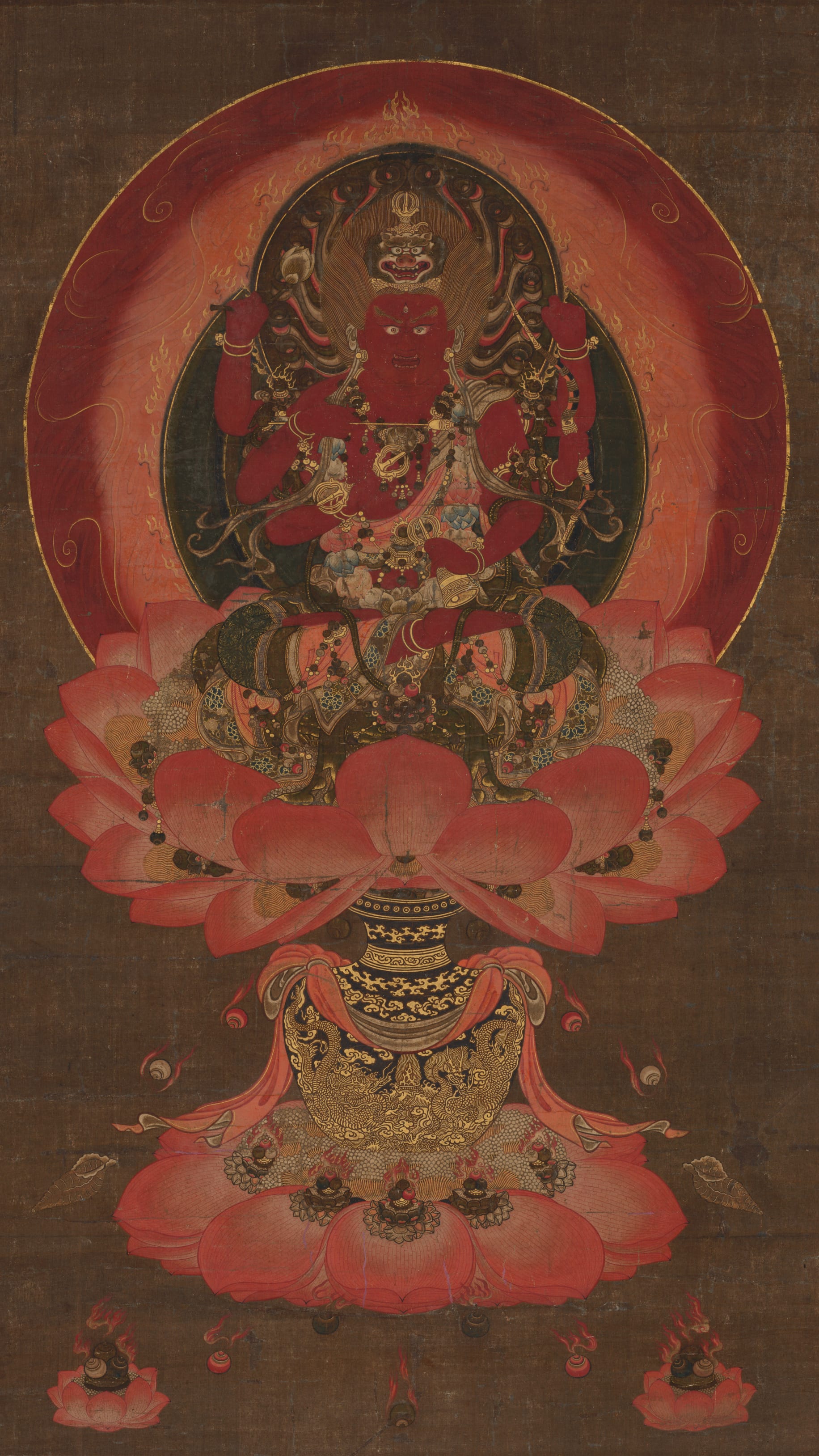 Dark moody vertical iPhone background from a Japanese painting: fierce red Buddhist deity with multiple arms seated on a lotus throne, deep crimson circular halo, large pink lotus petals, dark brown ground