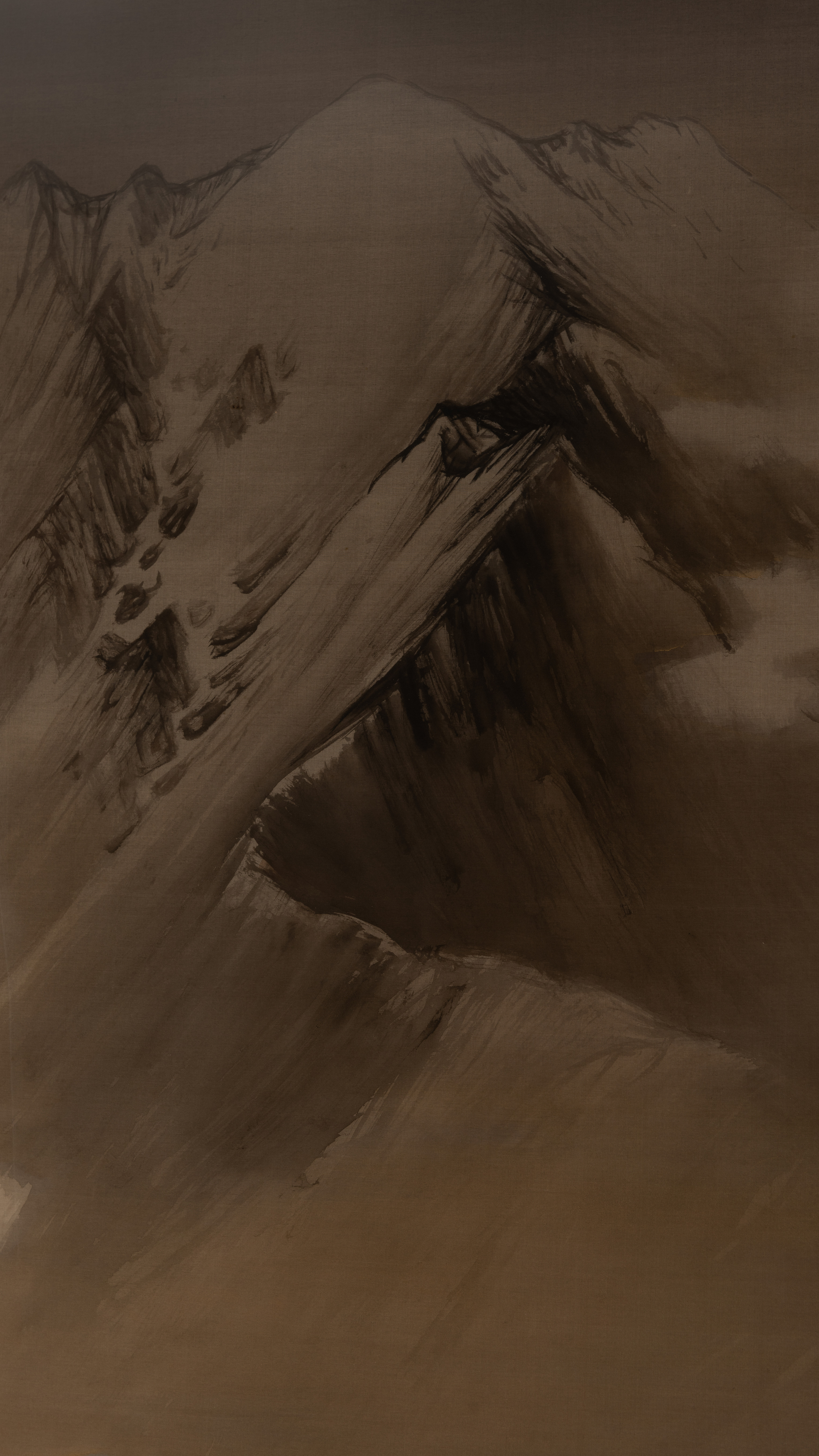 Dark moody vertical iPhone background from a Japanese painting: a snow-streaked mountain ridge in ink wash, pale slopes cut by black gullies and a thin dark treeline, a bare brown shoulder of rock across the foreground, everything sunk in warm shadow
