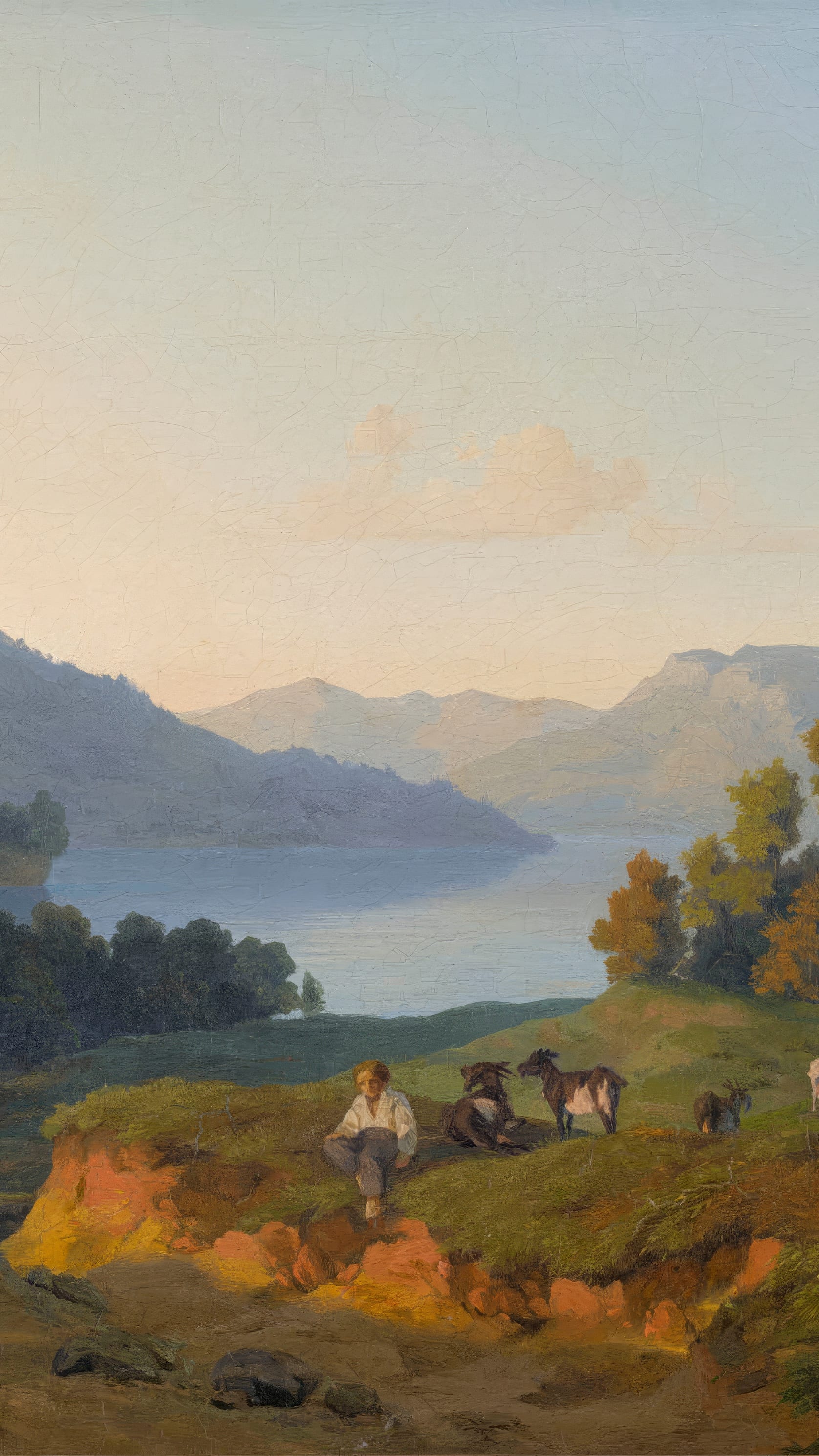 Vertical iPhone background from a painting: a pale evening sky over a long blue mountain lake, wooded ridges folding back into haze, and on the near bank a boy sitting in the grass beside two goats