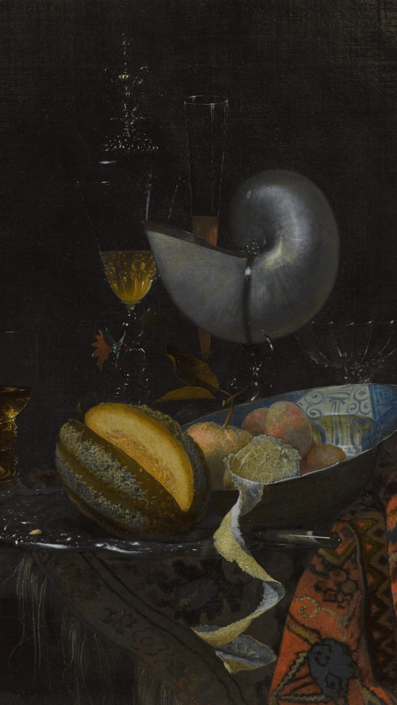 Dark academia vertical iPhone background from a painting: a silver-mounted nautilus cup tipped on its side beside wine glasses and a cut melon, a blue-and-white porcelain bowl of peaches on a dark cloth