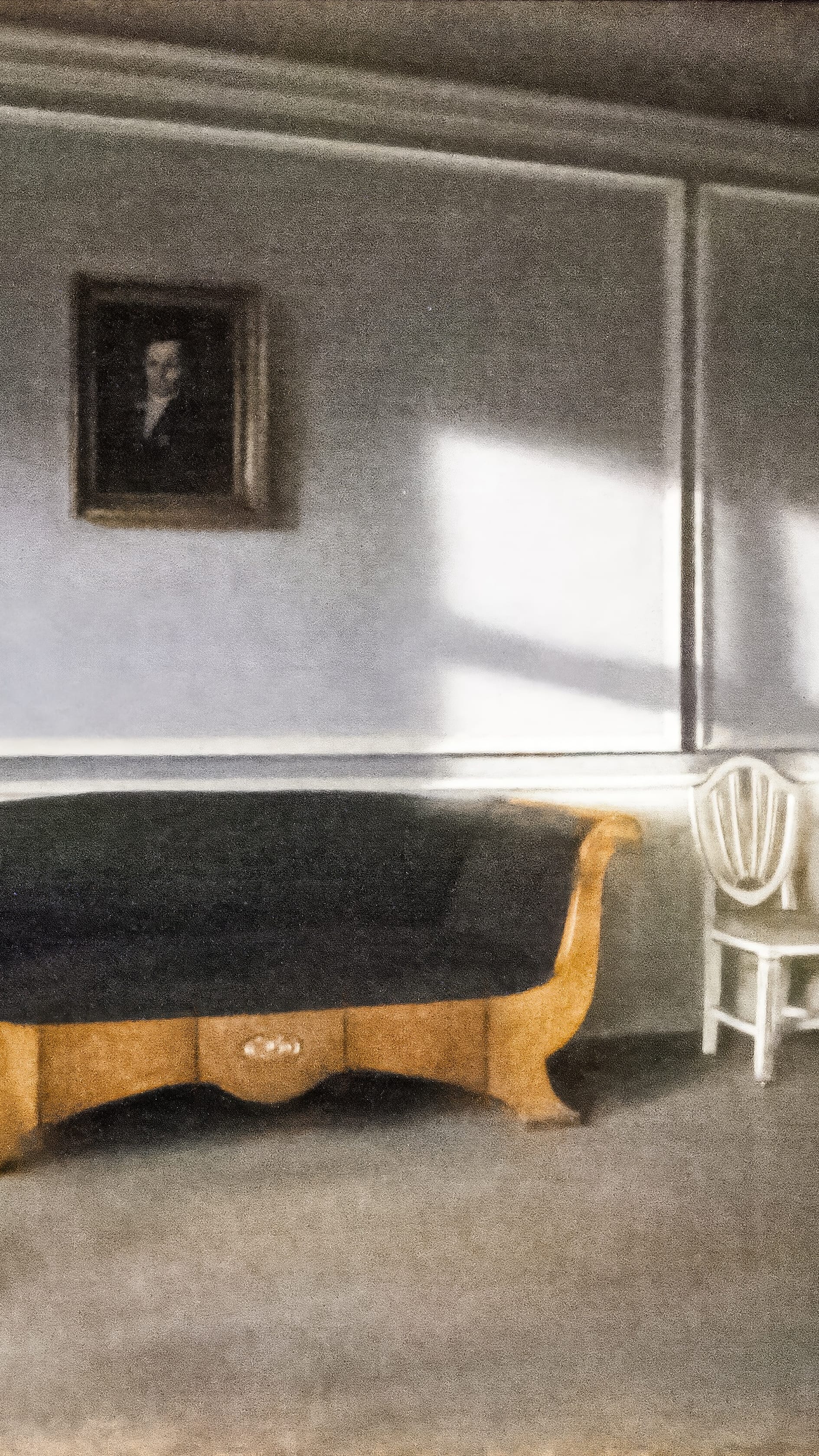 Vertical iPhone background from a painting: an empty grey room with a small dark portrait on the wall, a slab of sunlight lying across the plaster beside it, and a pale wooden sofa with black upholstery below