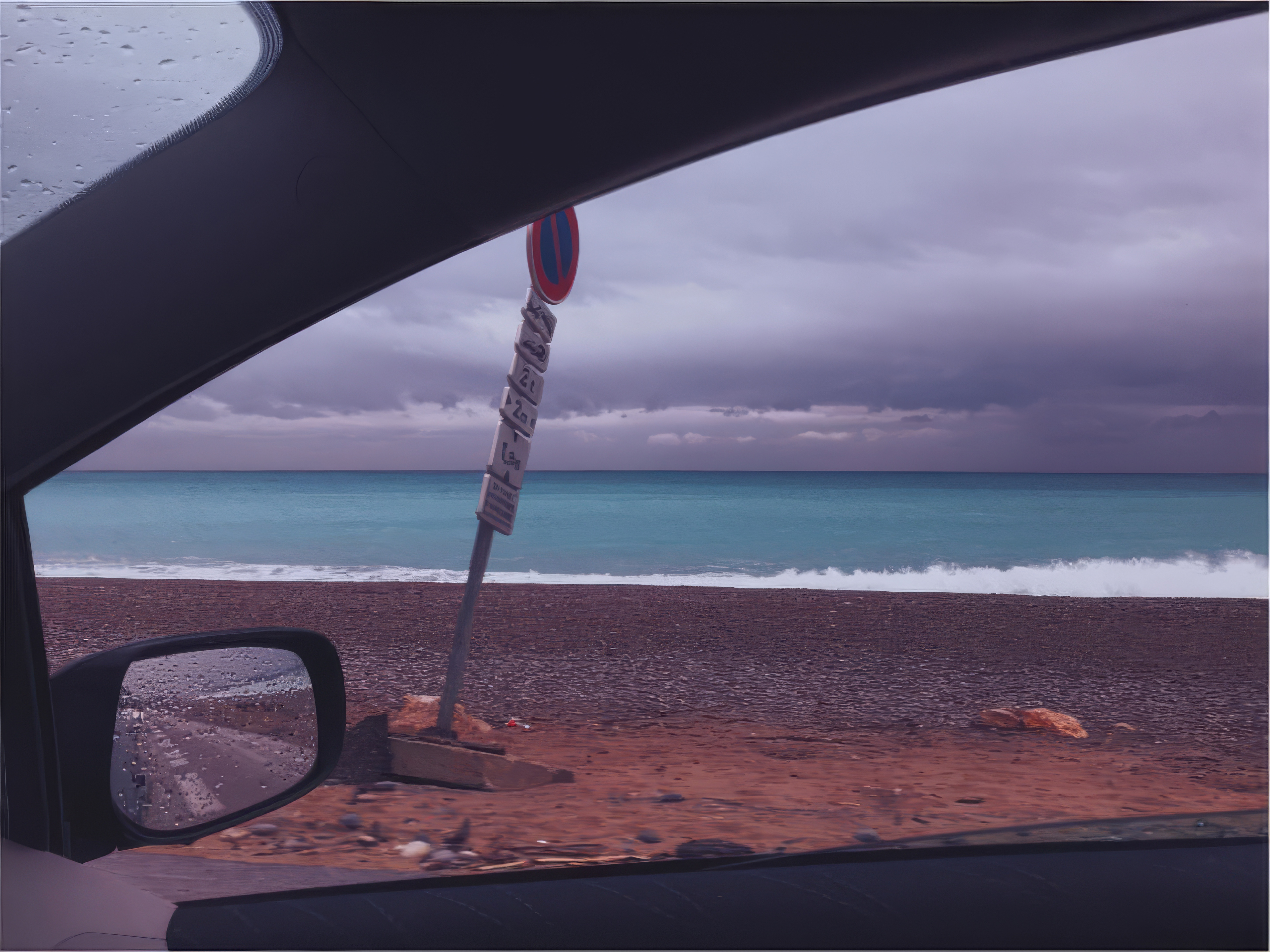 Desktop wallpaper photo: a car side mirror against a stormy beach horizon, dark clouds gathering