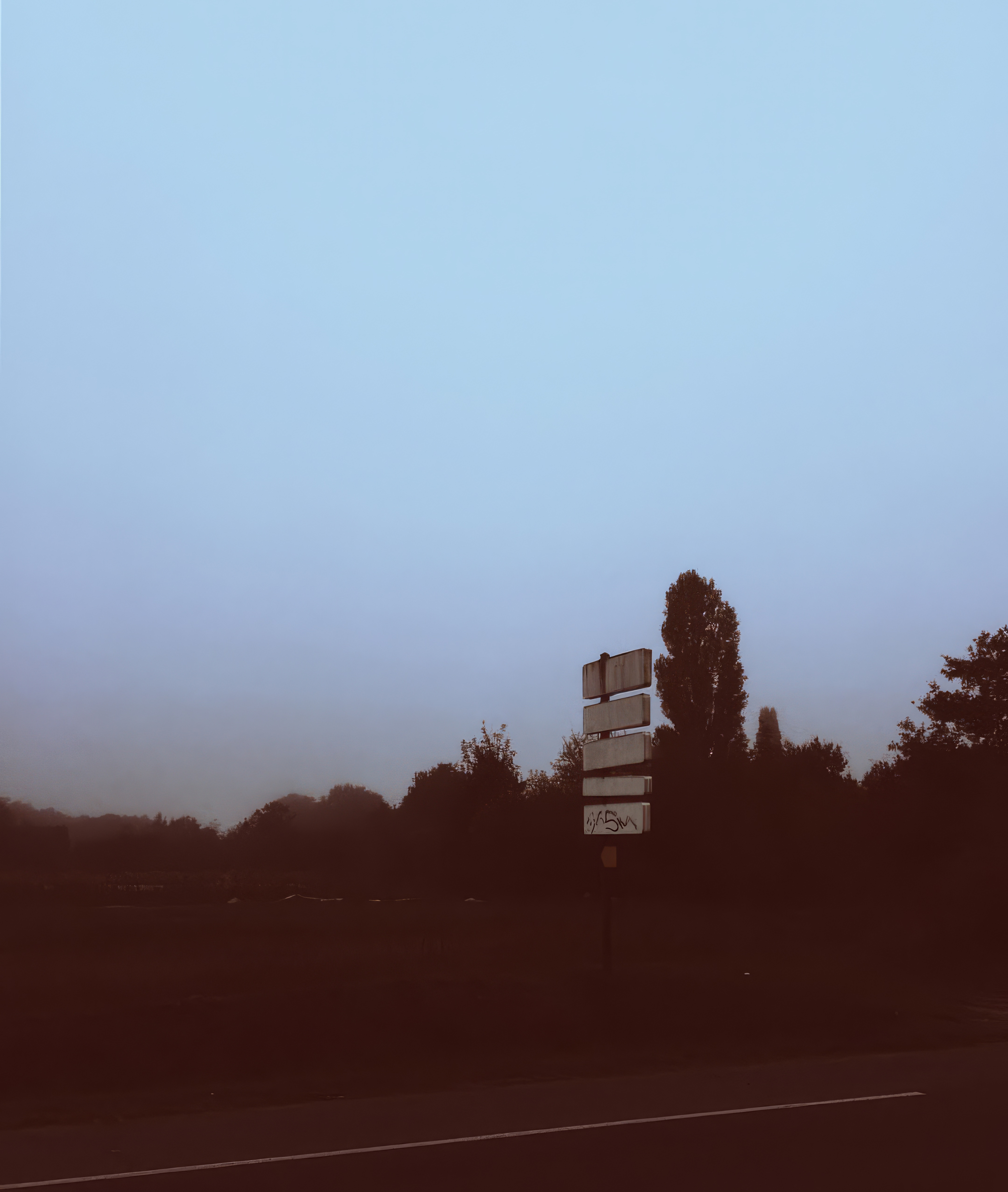Phone wallpaper photo: a cluster of road signs against a hazy dusk sky, warm and desaturated