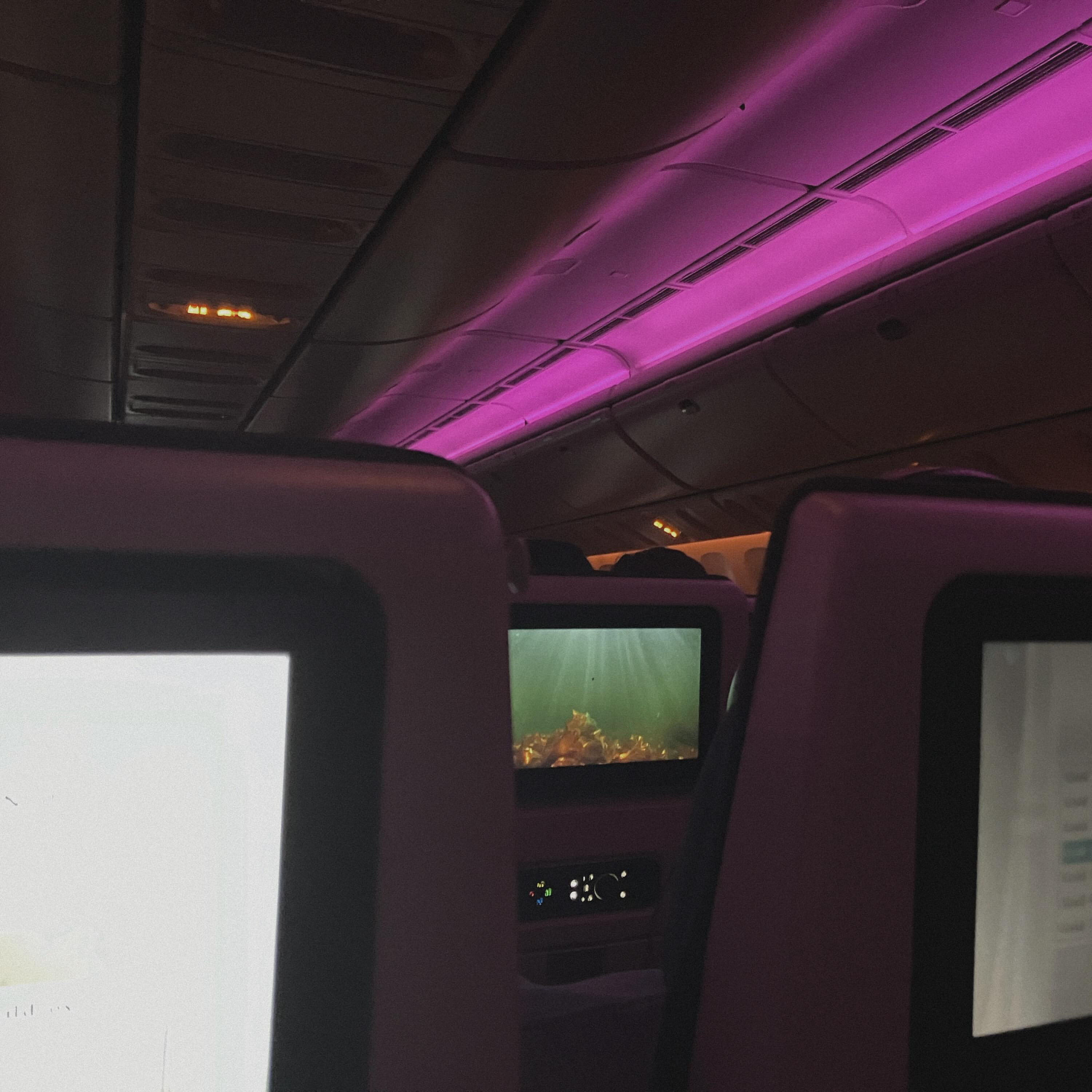 Phone wallpaper photo: an empty train cabin lit in magenta, seats and screens in shadow