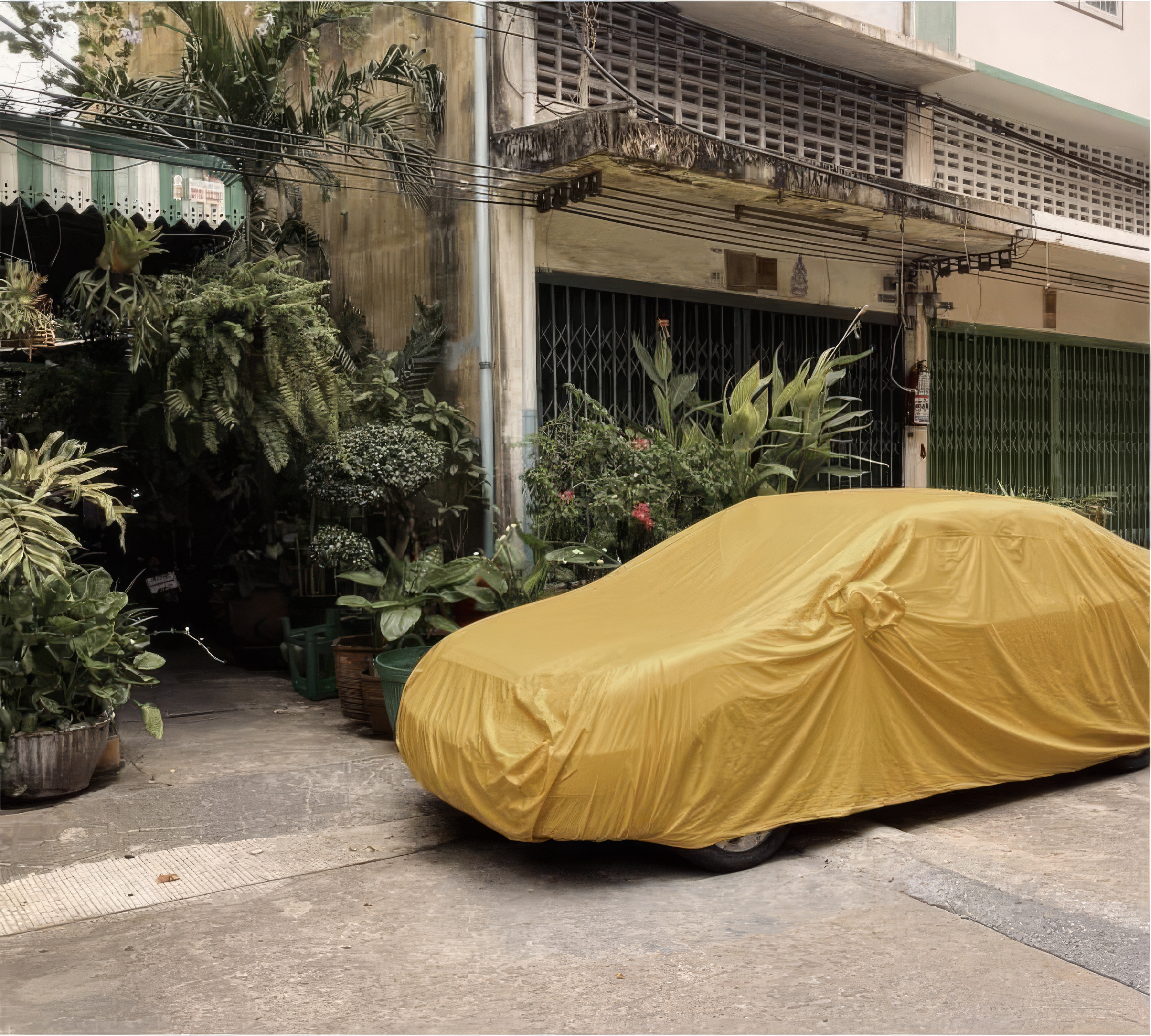 Desktop wallpaper photo: a car under a yellow cover parked in a leafy courtyard, shuttered windows above